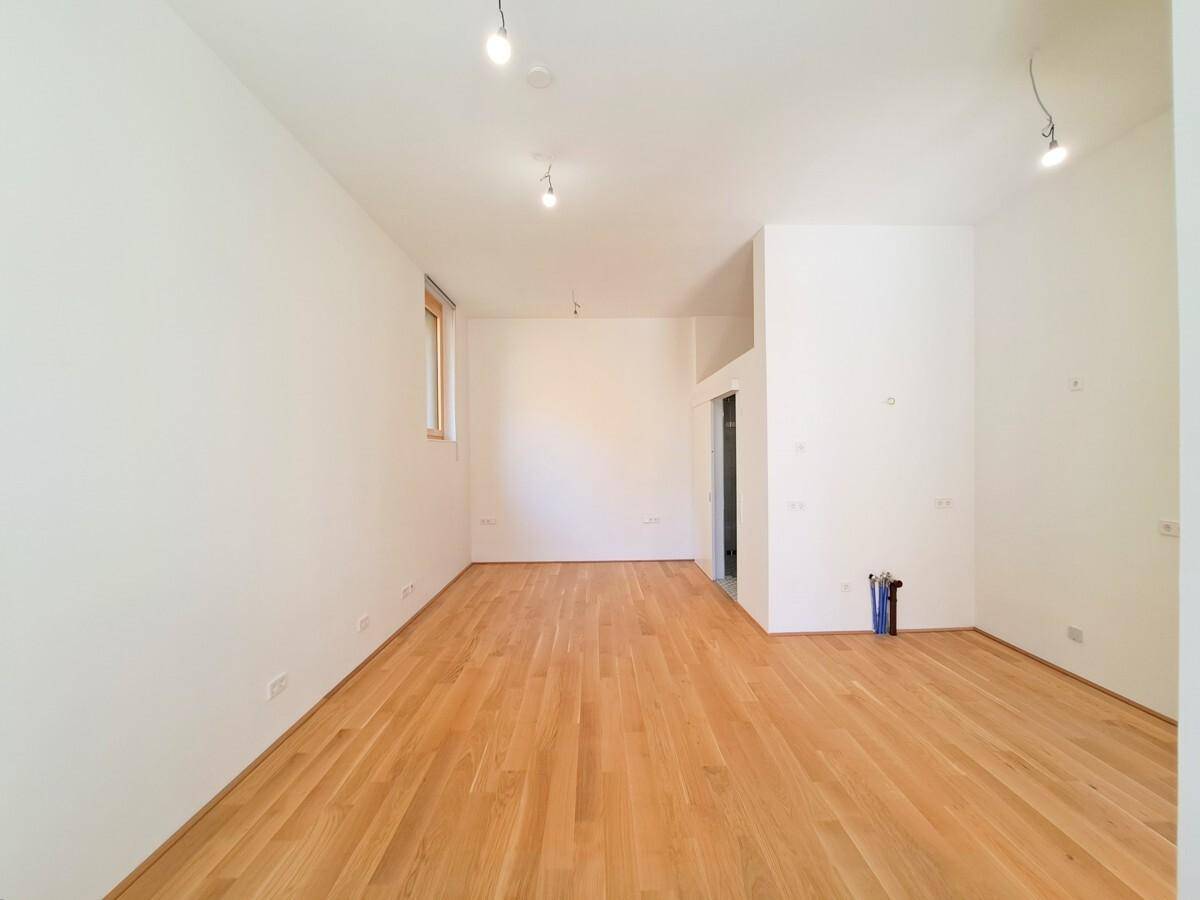 Heller Wohnraum mit Holzboden und Zugang zu einem weiteren Bereich, ideal für individuelle Gestaltung.