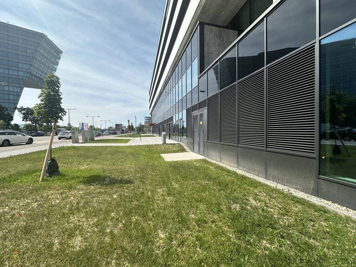 Die moderne Fassade eines Geschäftsgebäudes mit großen Glasflächen und einer belebten Straße.