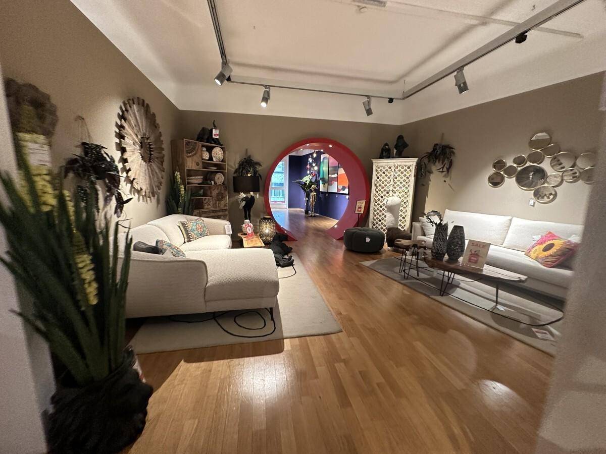 Heller Verkaufsraum mit Holzboden, modernen Sofas und dekorativen Wandelementen.
