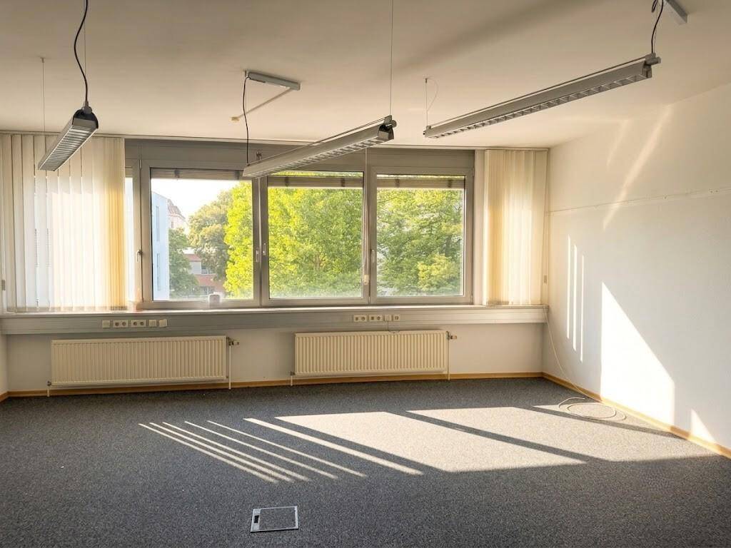 Geräumiges Büro mit Teppichboden, großen Fenstern und Blick ins Grüne.