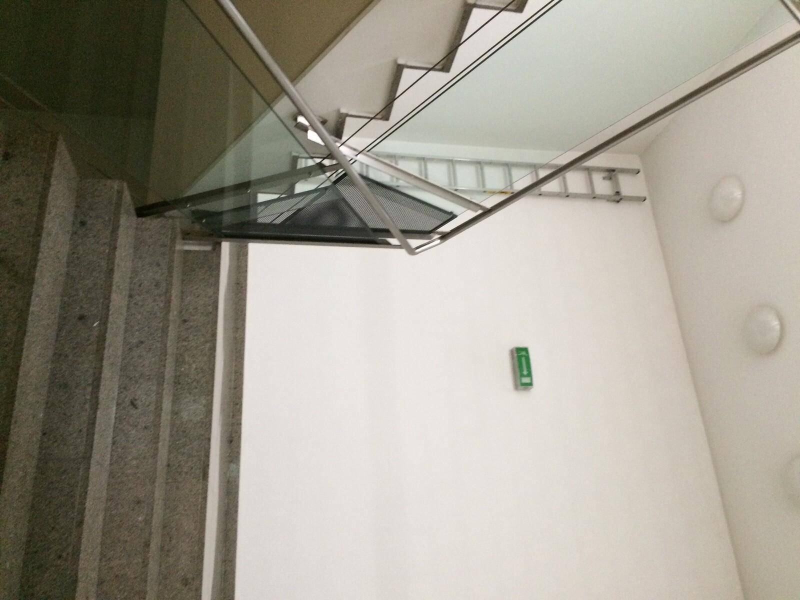 Modernes Treppenhaus mit Granitstufen, Glasgeländer und viel natürlichem Licht von oben.