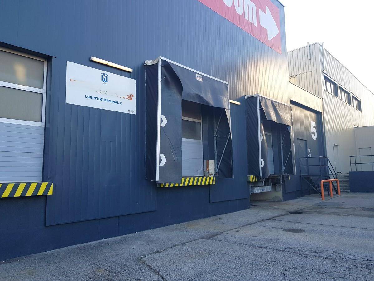 Laderampen eines Logistikterminals mit blauer Fassade und gelb-schwarzen Markierungen.