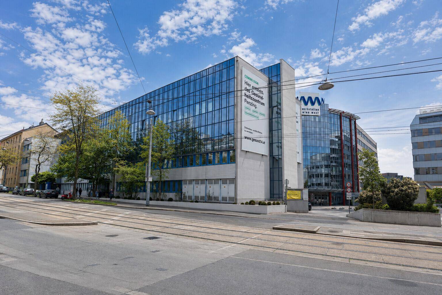 Moderne Bürogebäude mit Glasfassaden und Werbebannern entlang einer städtischen Straße.