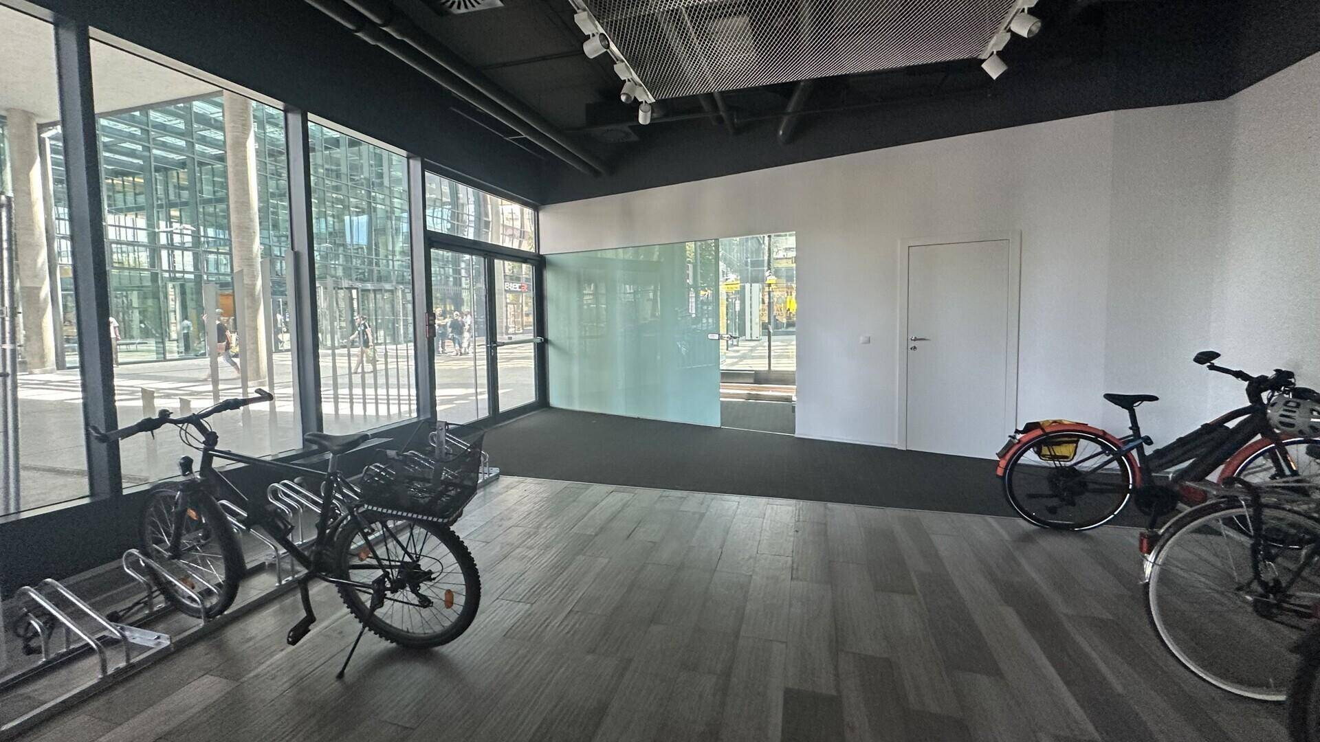 Heller Fahrradraum mit großen Glasfenstern und modernen Fahrradständern, der viel Tageslicht bietet.