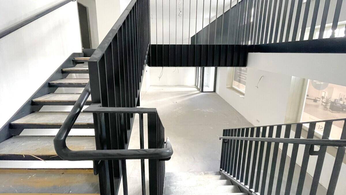 Moderne schwarze Metalltreppe mit Holzstufen, die verschiedene Ebenen des Gebäudes verbindet.