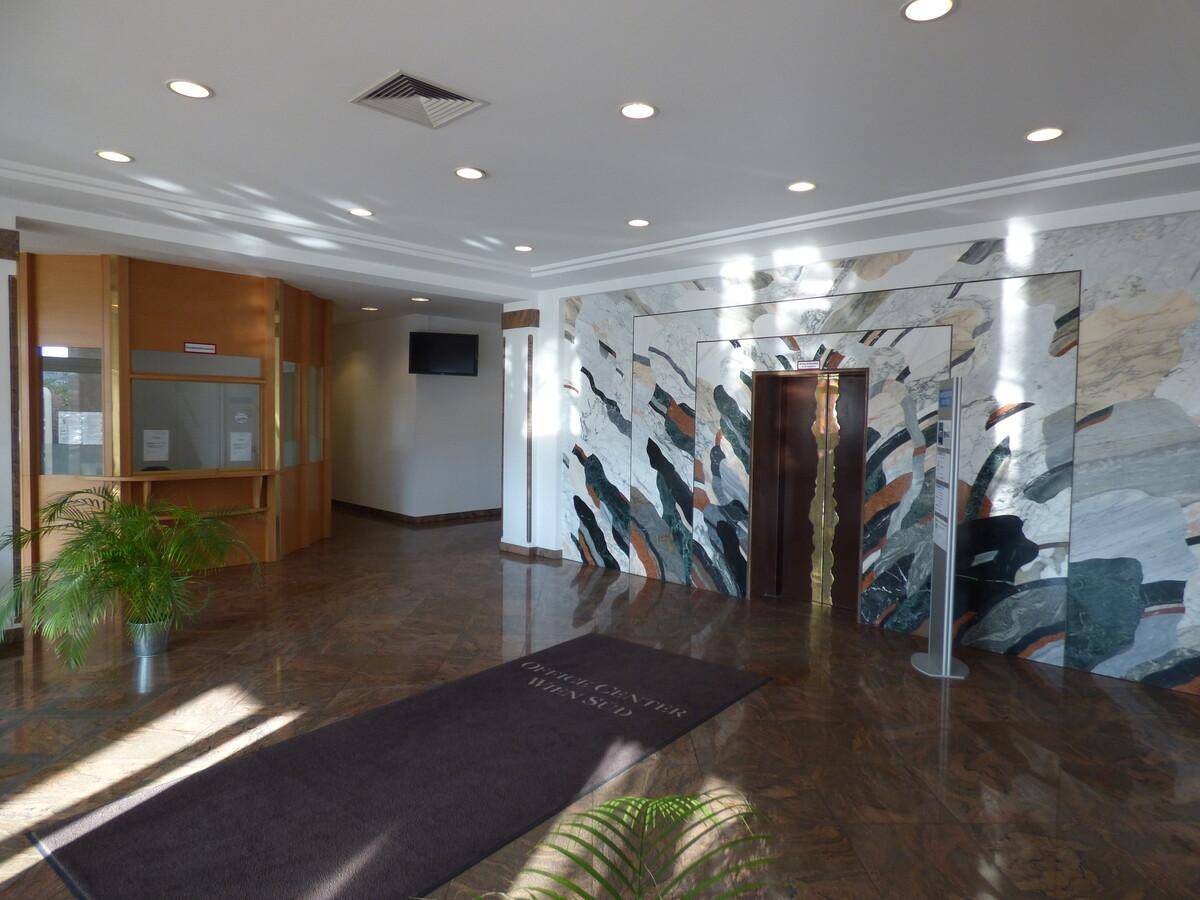Elegante Lobby mit Marmorboden, Rezeption und Aufzug, beleuchtet von Einbaustrahlern.