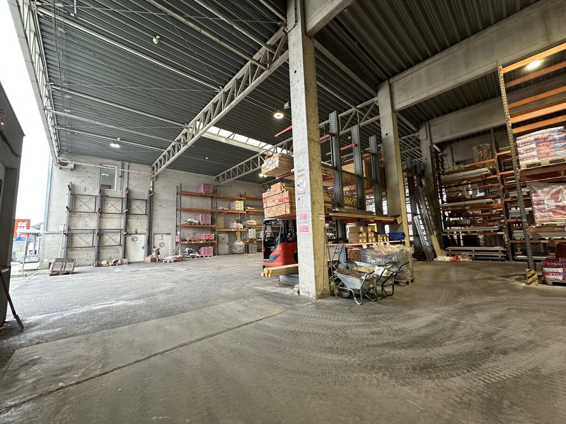Geräumiger Lagerbereich mit hohen Decken, Betonboden und robusten Regalsystemen für Materialien.