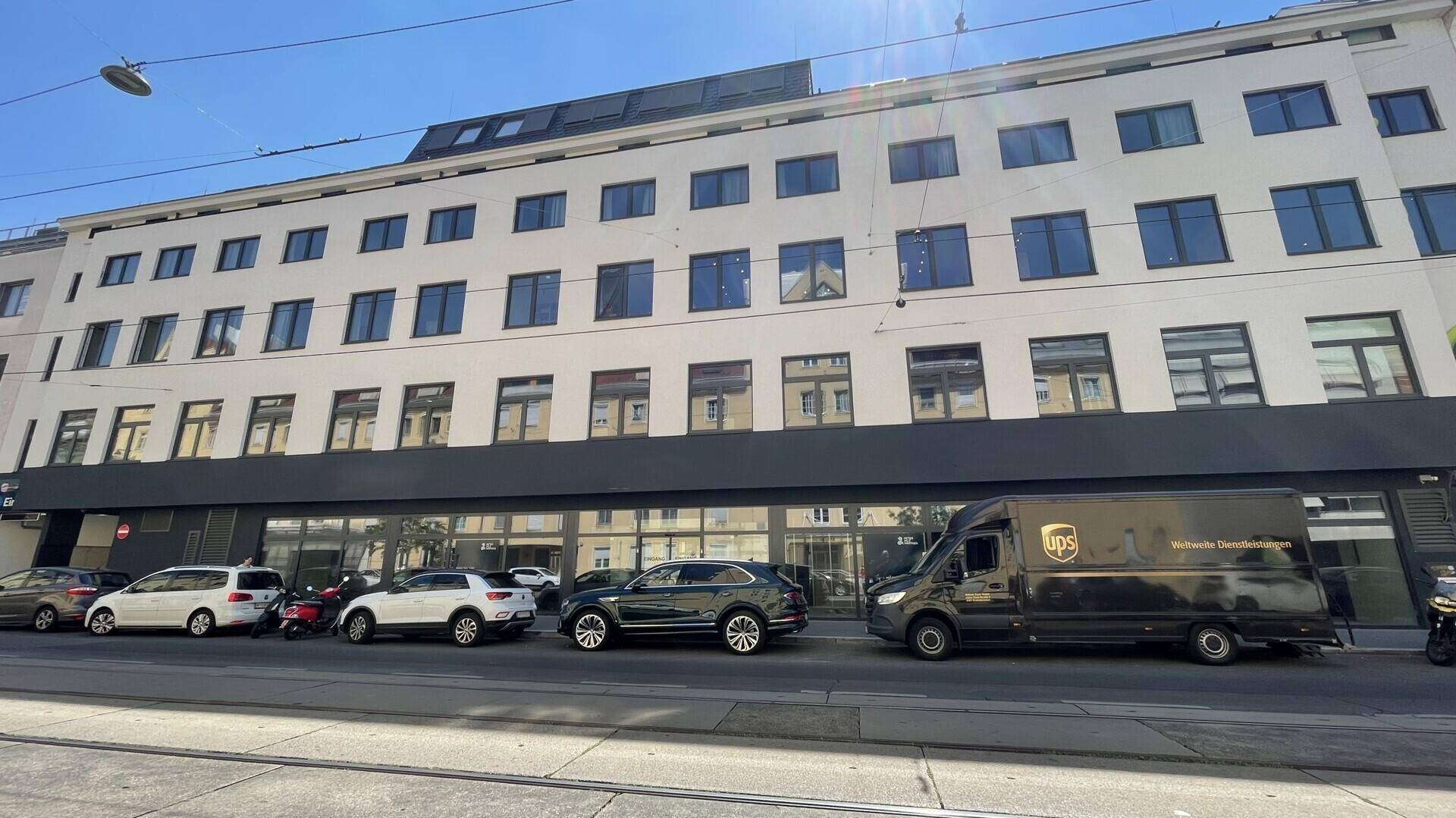 Eine weitere Außenansicht des modernen Gebäudes mit geparkten Autos entlang der Straße.