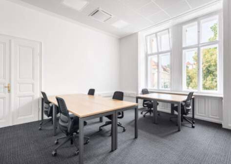 Helles Büro mit großen Fenstern, Teppichboden und mehreren Schreibtischen für effiziente Arbeitsplätze.