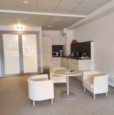 Bürobereich mit kleiner Küchenzeile, Sitzgelegenheiten und Teppichboden, ideal für Pausen.