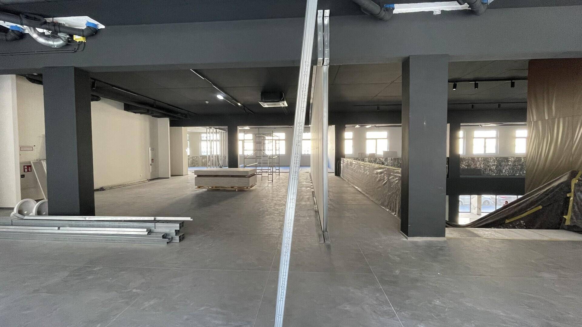 Geräumiger Bürobereich im Rohbau mit Säulen und Materialien für den Innenausbau.