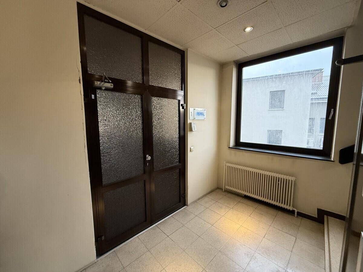 Eingangsbereich mit gefliestem Boden, einer großen Glastür und einem Fenster mit Blick nach draußen.