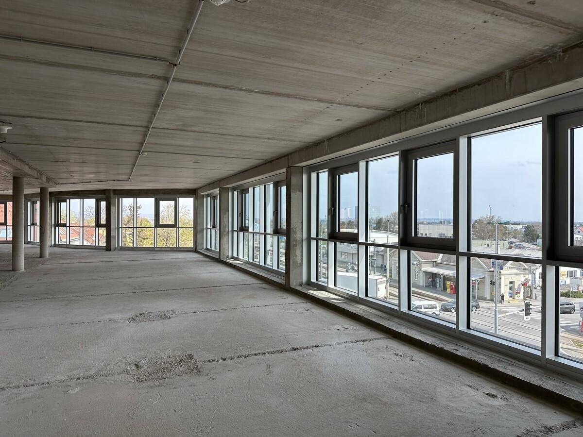 Heller Gewerberaum mit langer Fensterfront, die einen Blick auf die Straße und die städtische Umgebung bietet.