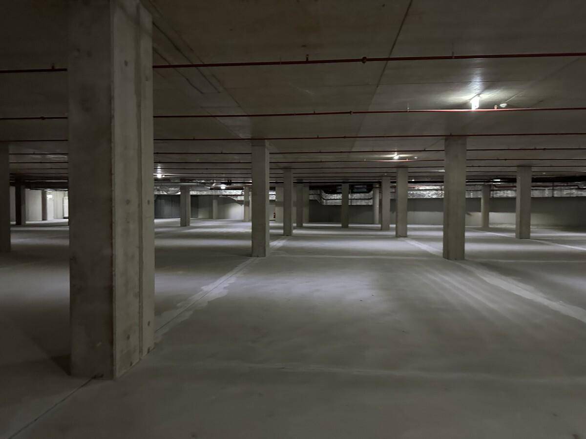 Weitläufige Tiefgarage mit zahlreichen Betonstützen und minimalistischer Beleuchtung.
