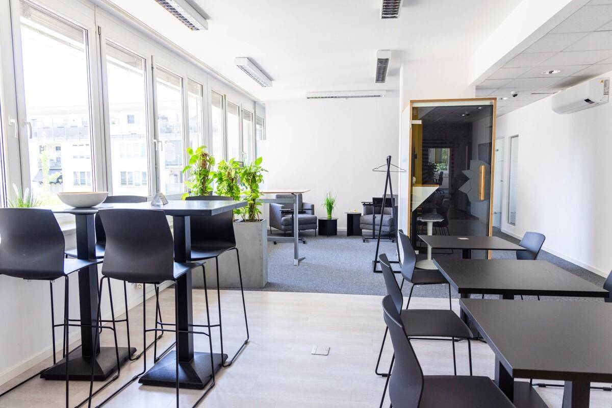 Offener Bürobereich mit verschiedenen Sitzgelegenheiten, Stehtischen und Lounge-Bereich, ideal für flexible Arbeitsweisen.