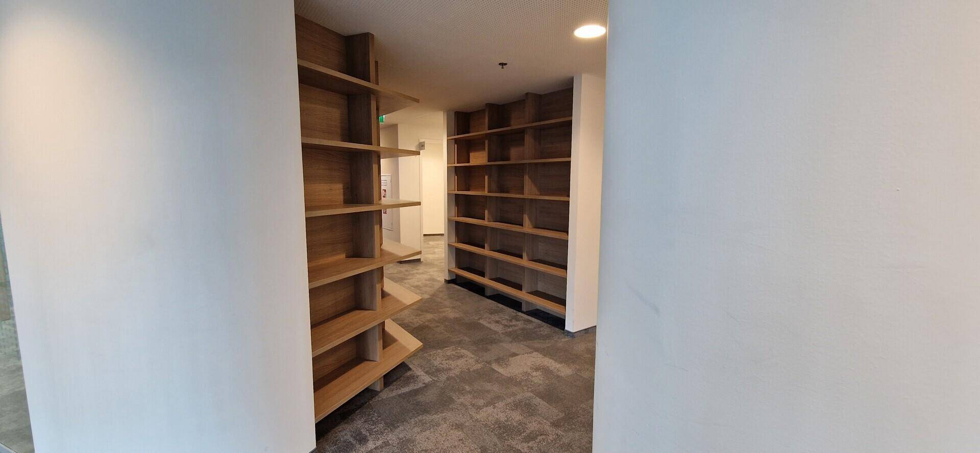 Gangbereich mit raumhohen, eingebauten Holzregalen, die viel Stauraum bieten.