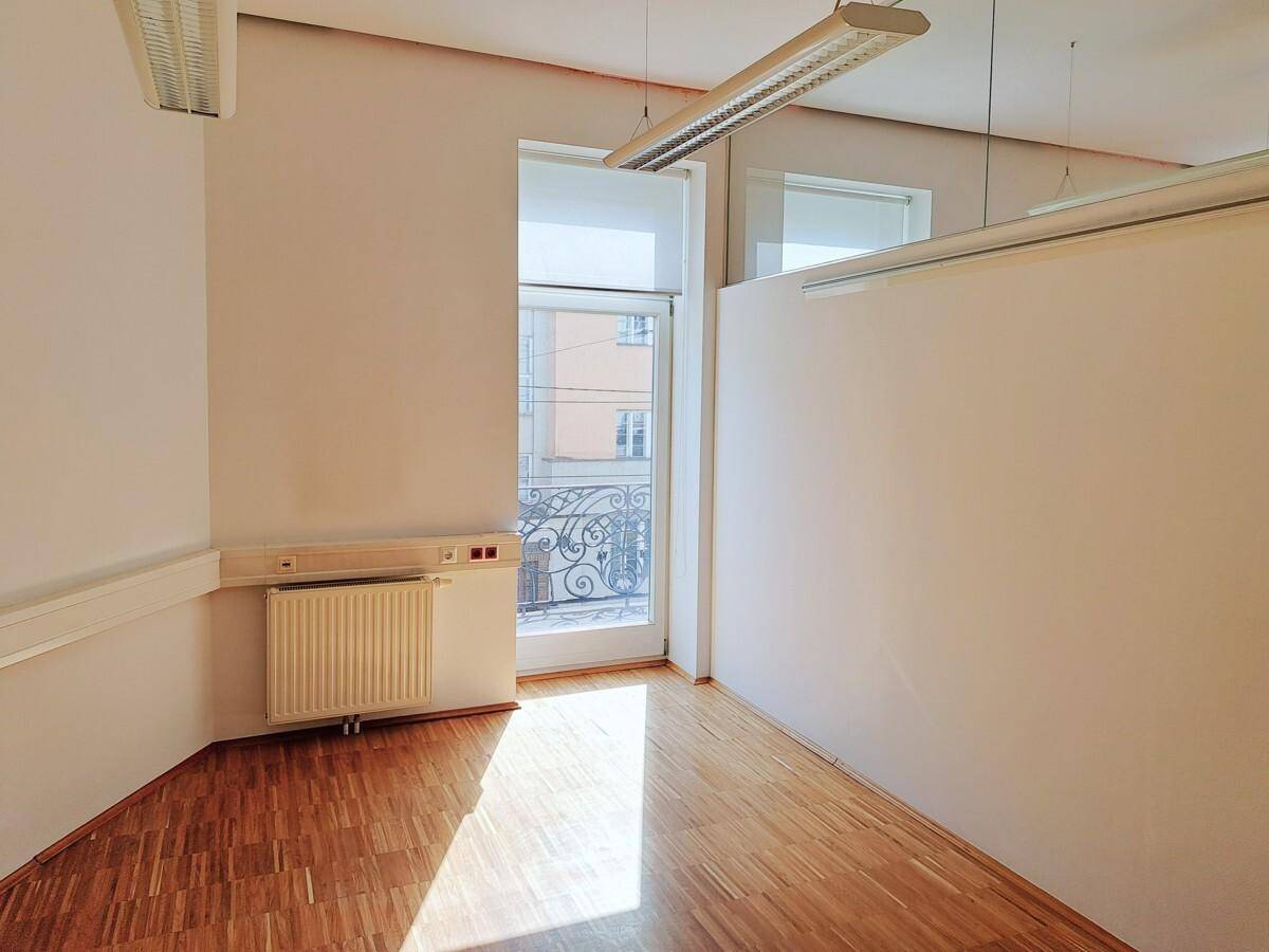 Helles Büro mit Zugang zu einem kleinen Balkon, Holzfußboden und viel Tageslicht.