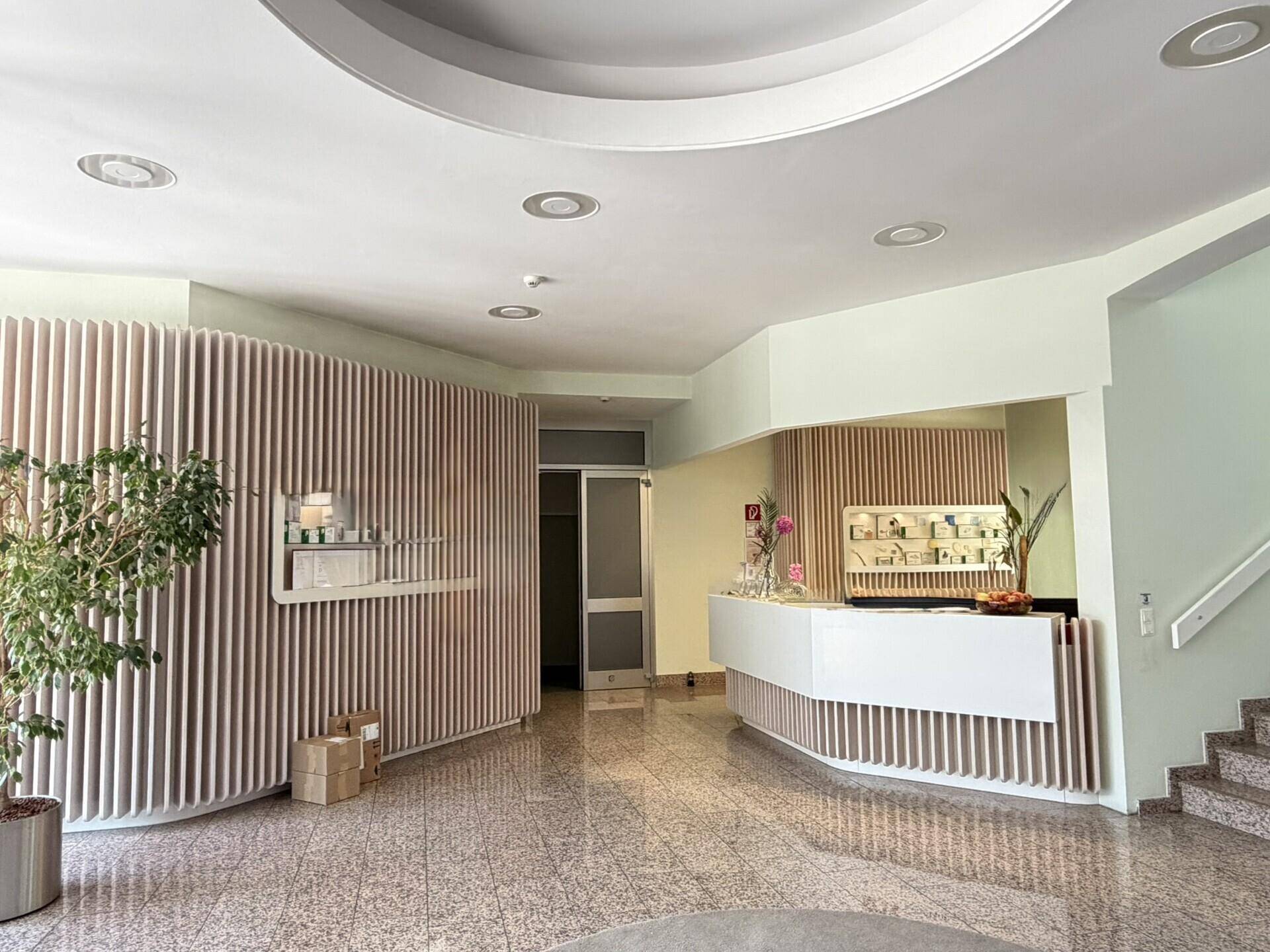 Heller Empfangsbereich mit moderner Theke, Holzlamellen und Terrazzoboden.