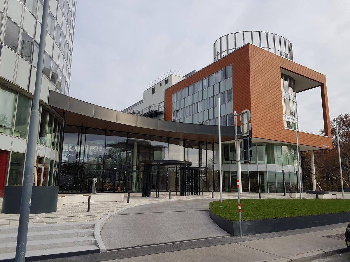 Ansicht eines modernen Bürokomplexes mit markanter Architektur, Glasfronten und einem einladenden Eingangsbereich.