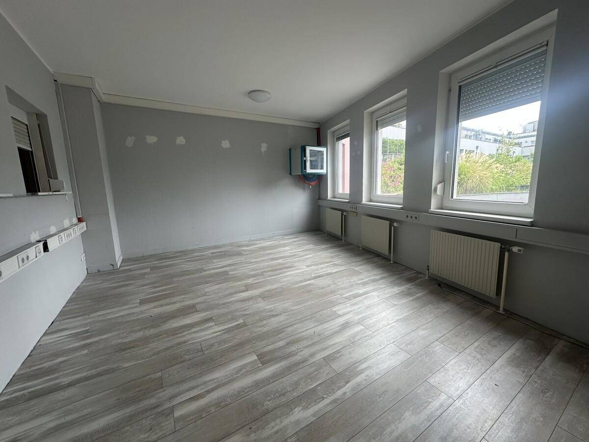 Büro mit grau gestrichenen Wänden und modernem Laminatboden, bereit zur individuellen Gestaltung.