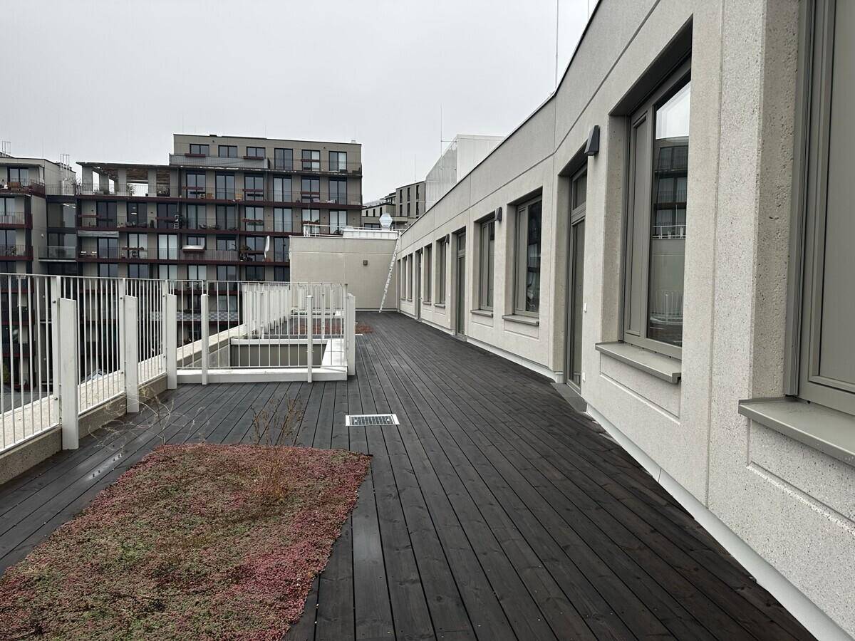 Große Dachterrasse mit Holzplanken und Blick auf die umliegenden Gebäude und die Landschaft.