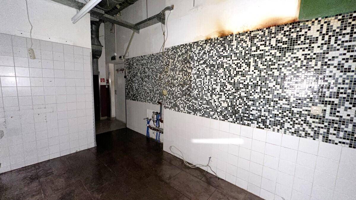 Gefliester Raum mit schwarz-weißen Mosaikfliesen an der Wand und sichtbaren Rohrleitungen.