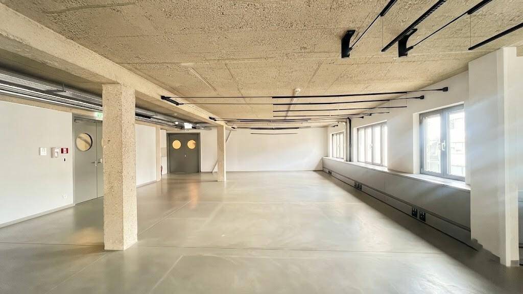 Weitläufiger, heller Gewerberaum mit Betonboden, hohen Decken und industriellem Charme, bereit zur Gestaltung.