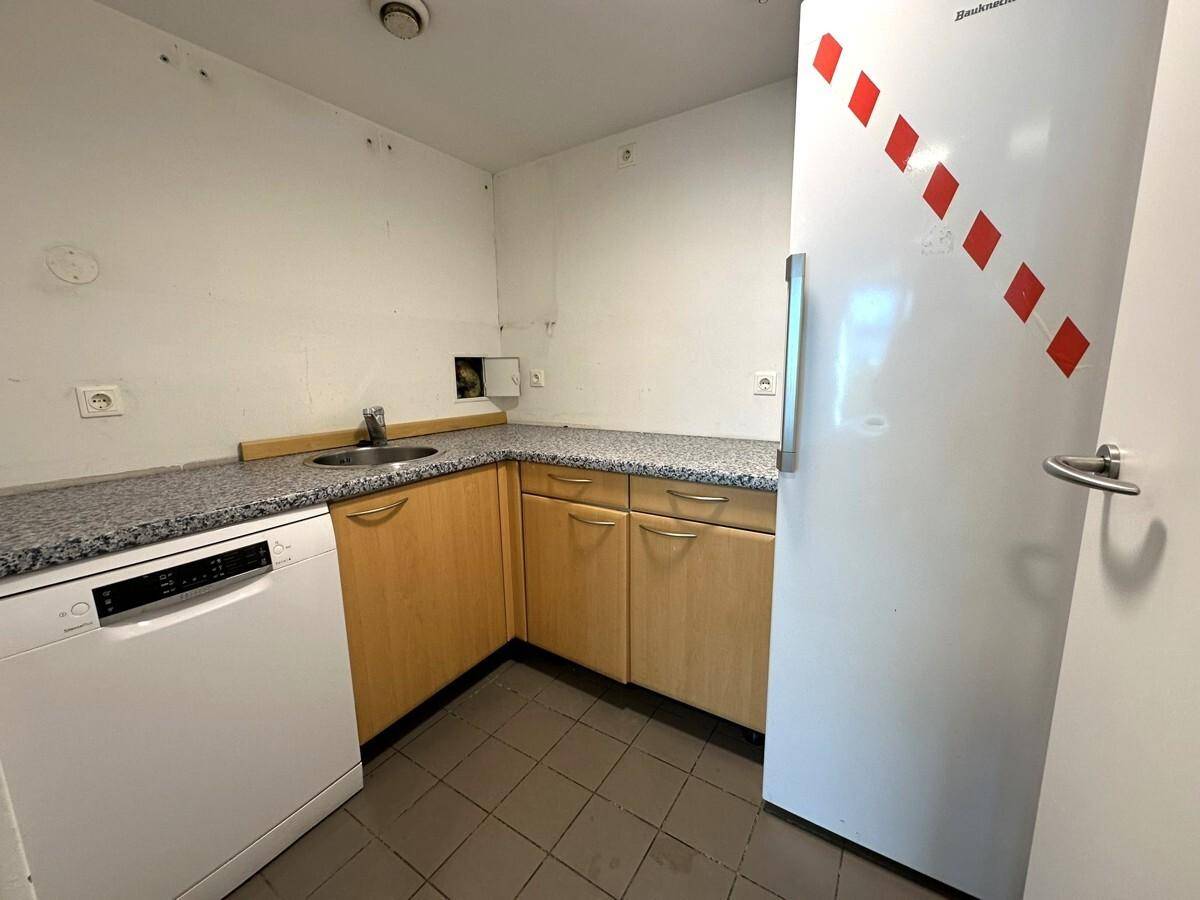 Kleine Küchenzeile mit Spüle, Geschirrspüler und Kühlschrank in funktionalem Design.