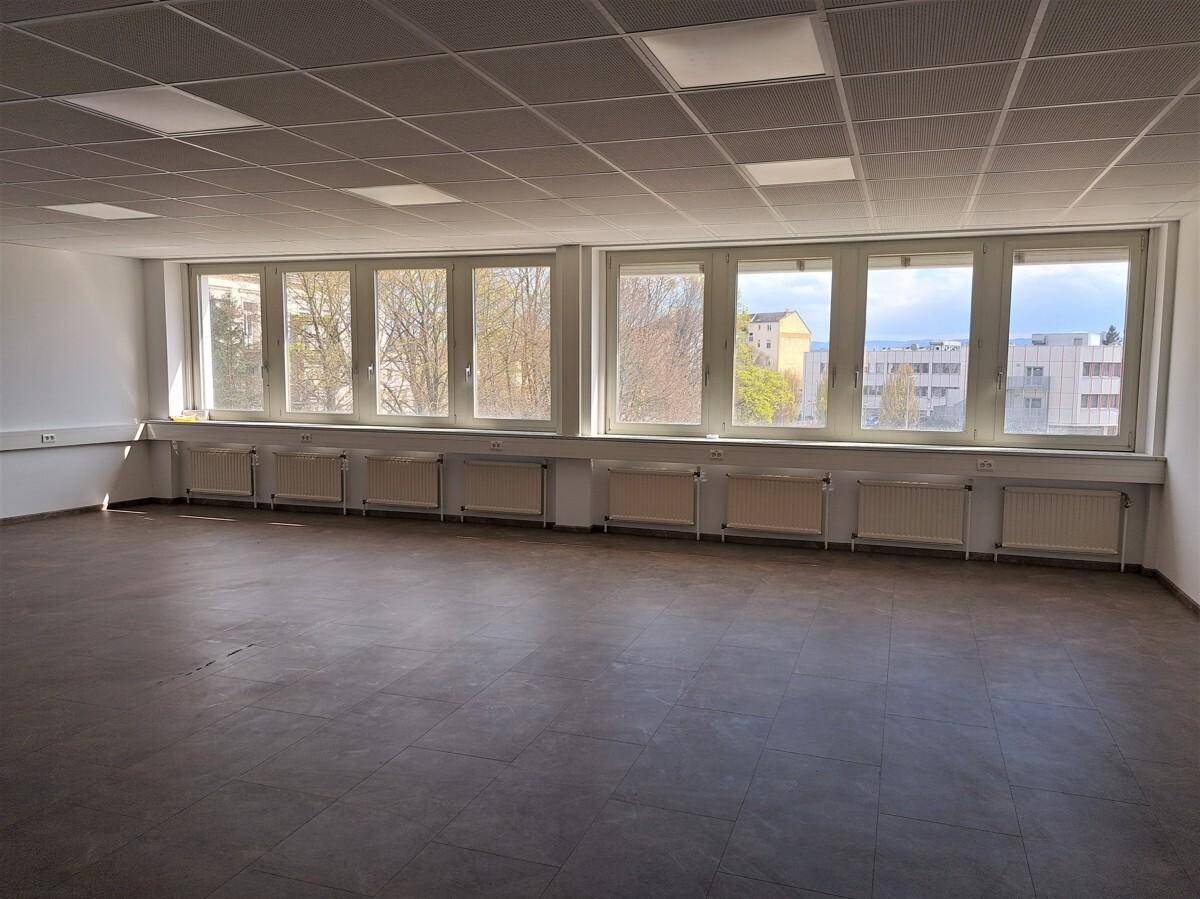 Geräumiger Büroraum mit vielen Fenstern, die eine weite Aussicht bieten und den Raum mit Licht füllen.