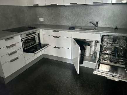 Moderne Einbauküche mit weißen Schränken, Induktionskochfeld, Backofen und Geschirrspüler.
