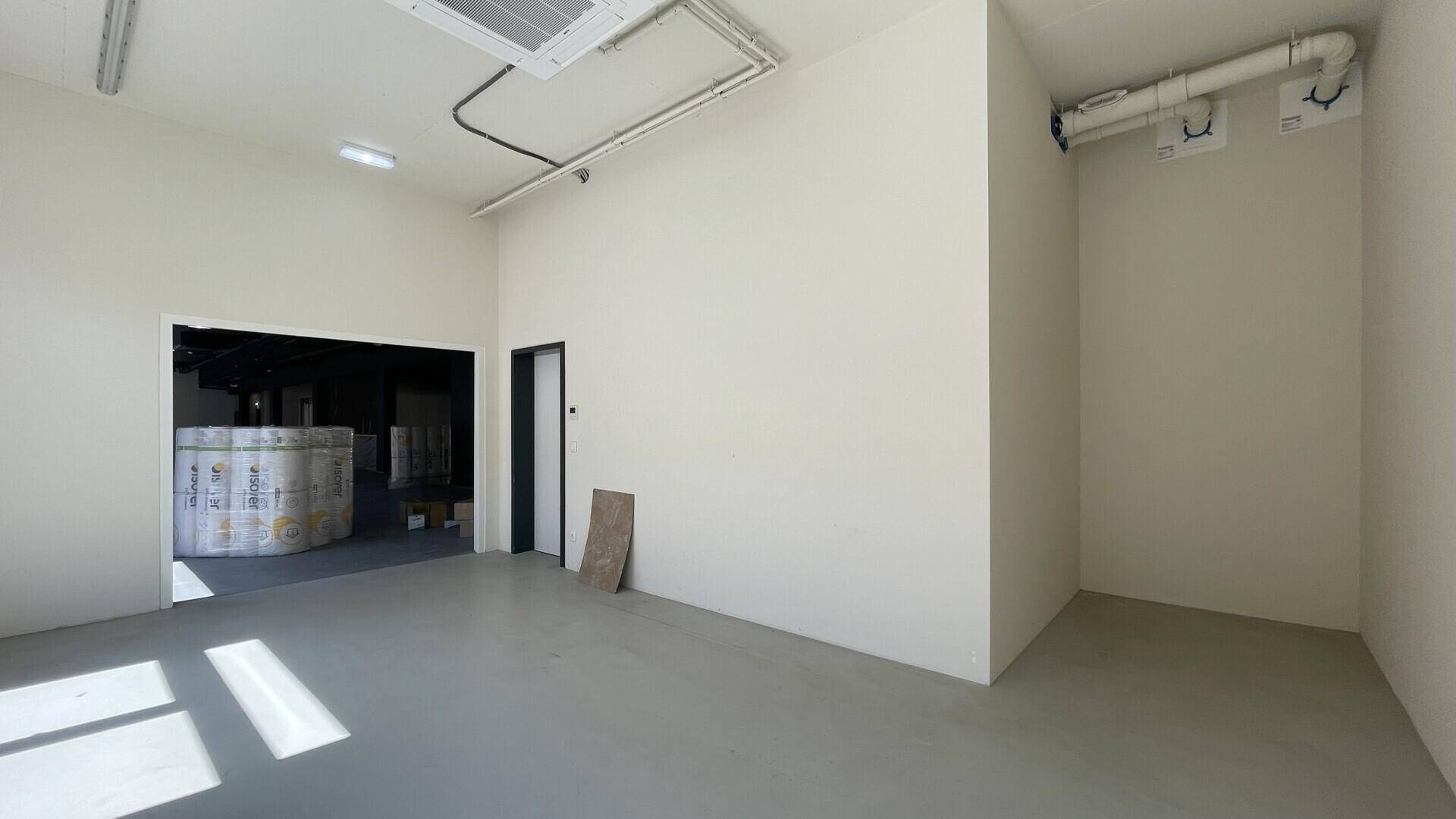 Kleinerer Raum mit hellen Wänden und sichtbaren Lüftungsrohren an der Decke.
