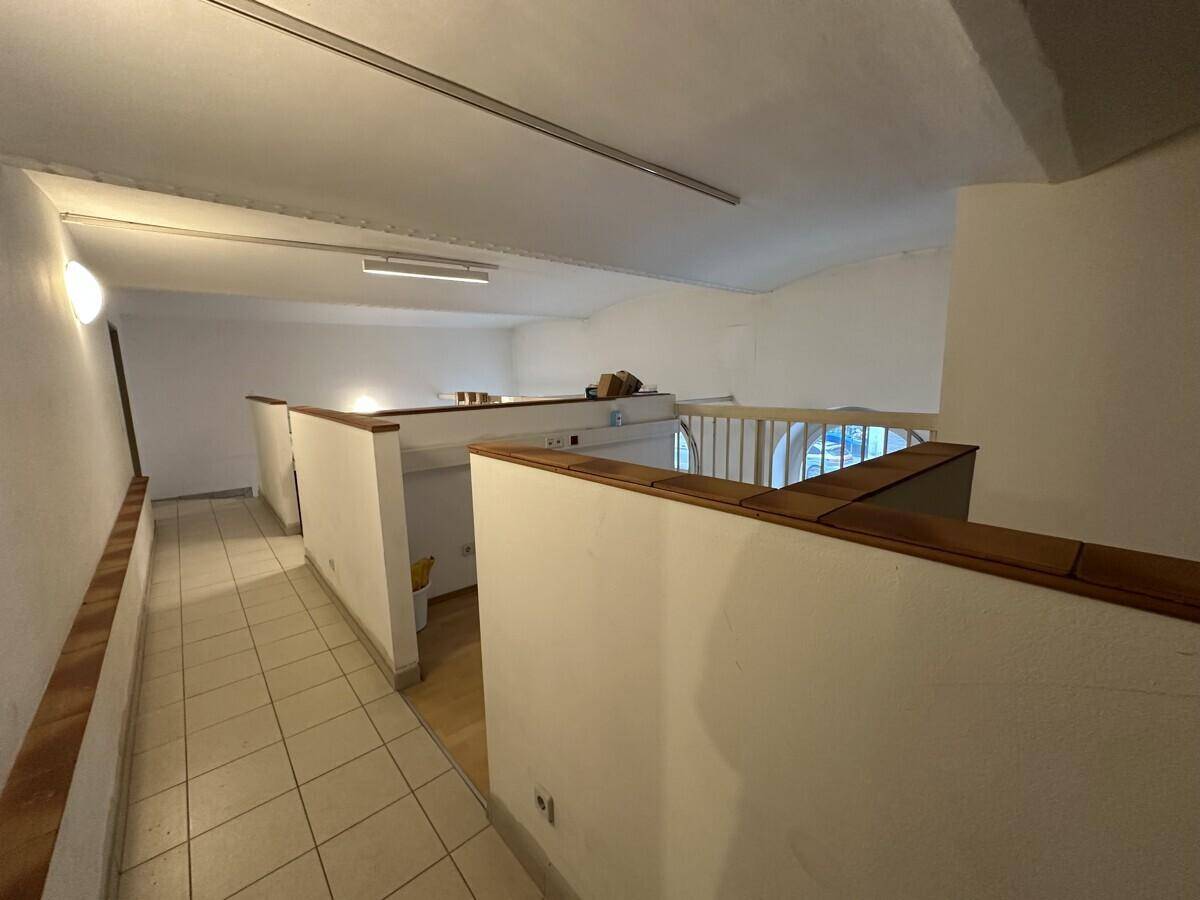 Obergeschoss eines Büros mit Fliesenboden und Holzgeländer, das den Blick auf den unteren Bereich freigibt.