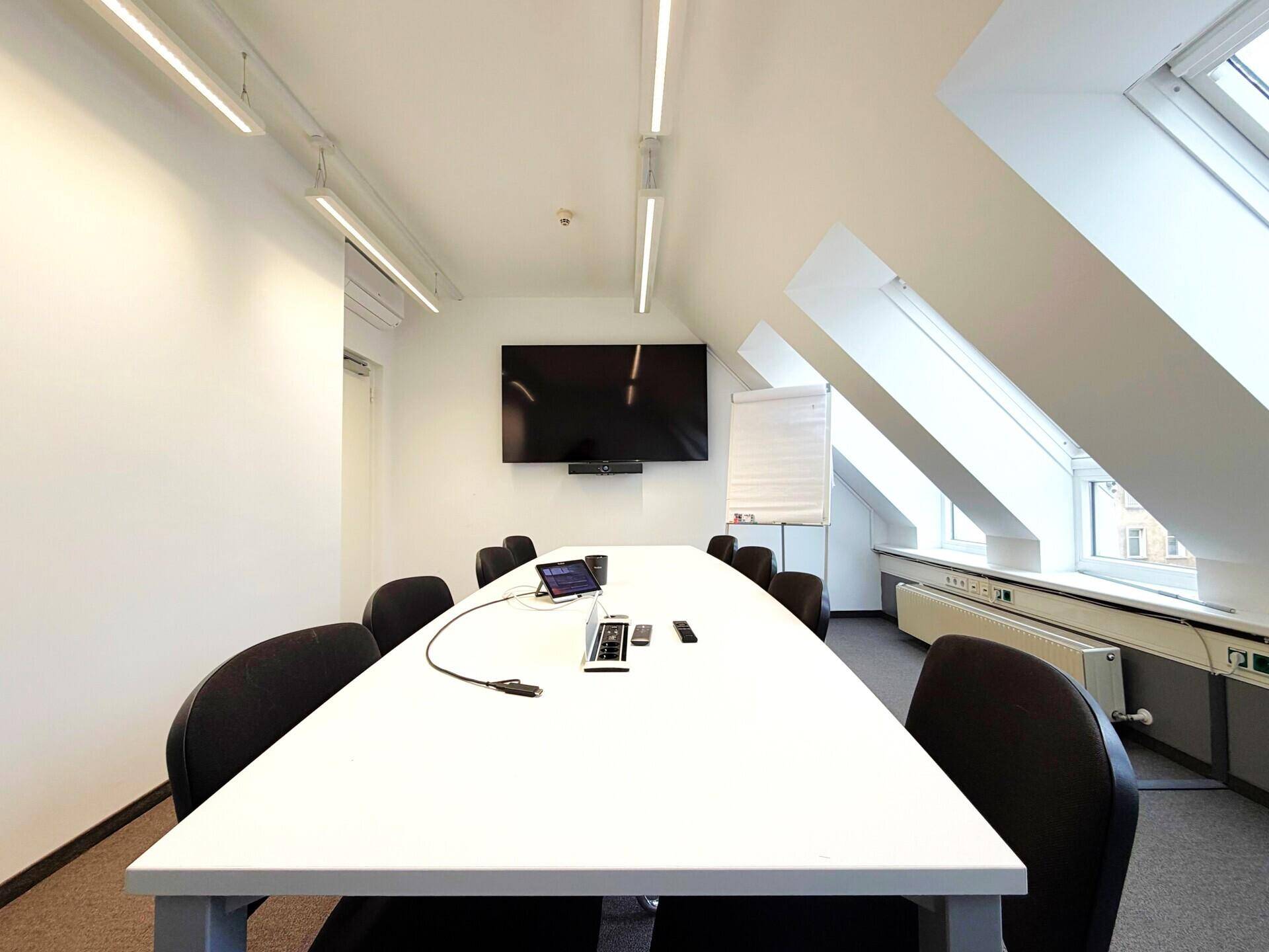 Geräumiges Büro mit mehreren Arbeitsplätzen, ergonomischen Stühlen und schrägen Dachfenstern.
