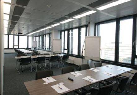 Großer Konferenz- oder Schulungsraum mit flexiblen Tischen, Stühlen und weitreichendem Stadtblick.