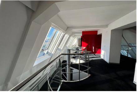 Offener Bürobereich im Dachgeschoss mit Mezzanine, schrägen Wänden und großen Dachfenstern.