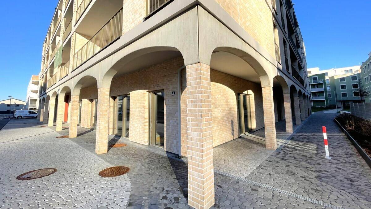 Detailansicht der modernen Fassade mit eleganten Bögen und hellen Ziegeln im Erdgeschossbereich.