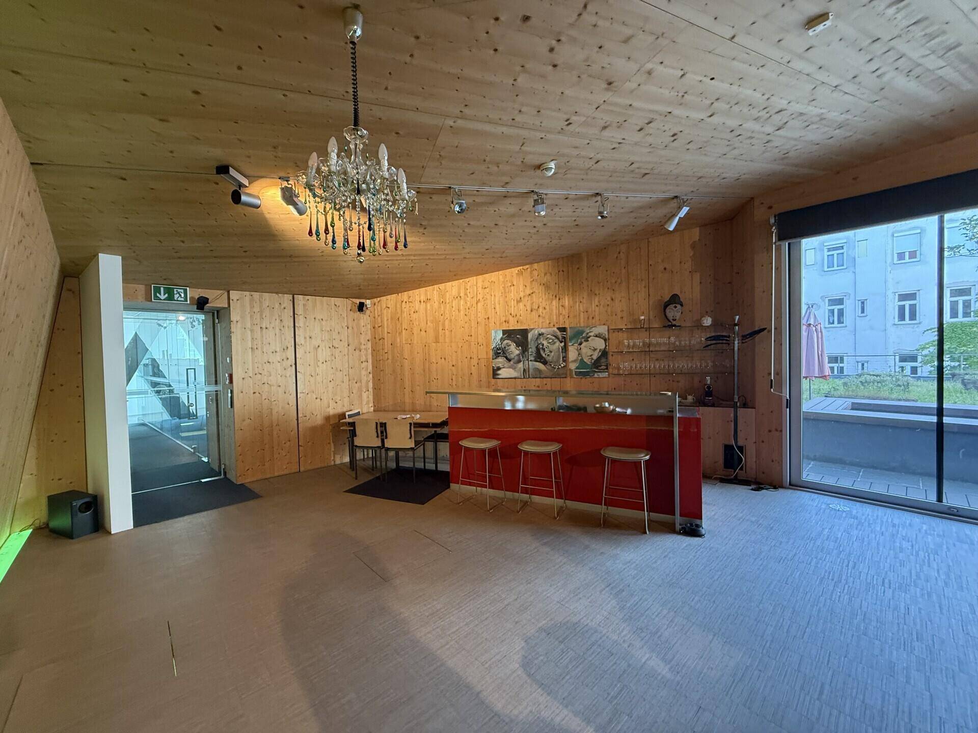 Gemütlicher Loungebereich mit Holzverkleidung, Bar und Kronleuchter, ideal für Veranstaltungen.