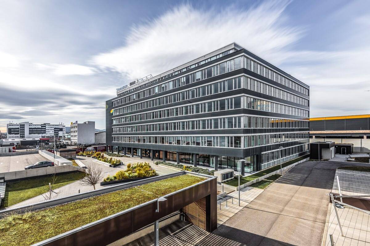Gesamtansicht des modernen Bürogebäudes mit begrüntem Dach und umliegenden Parkflächen.