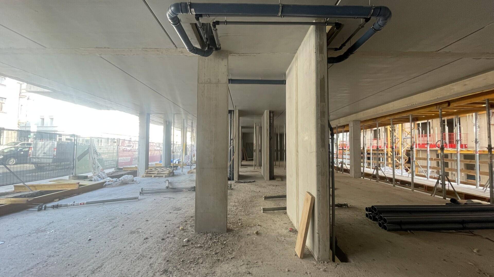 Rohbau-Innenraum mit Betonstützen, Decken und sichtbaren Rohrleitungen, bereit für den weiteren Ausbau.
