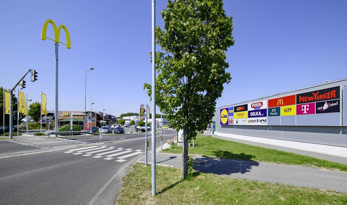 Außenansicht eines Gewerbegebiets mit Fast-Food-Restaurant, Geschäften und einer Straße.
