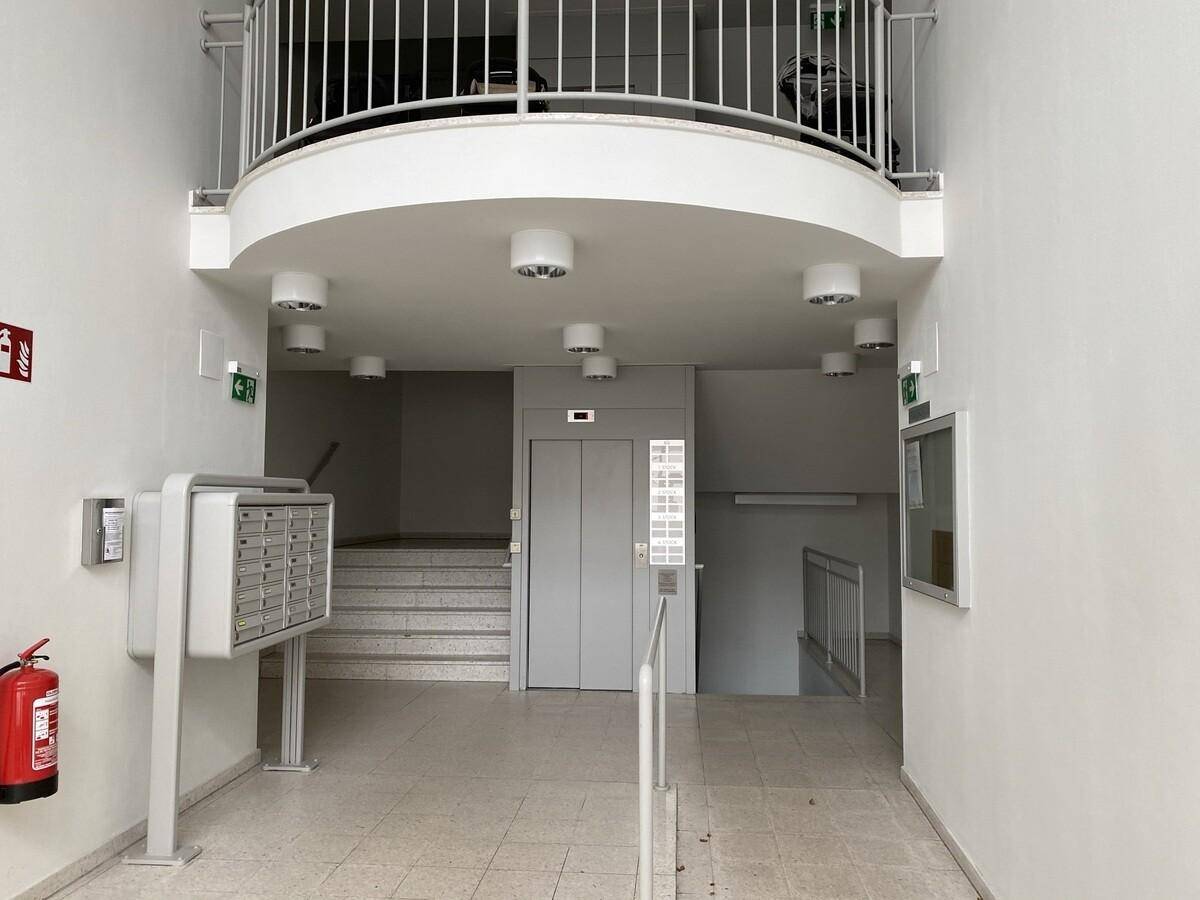 Heller Eingangsbereich eines Gebäudes mit Briefkästen, Treppe und einem modernen Aufzug.