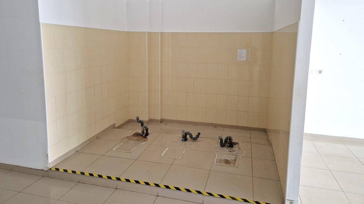 Kleiner gefliester Bereich mit Wasseranschlüssen und Abflüssen, möglicherweise für eine Küche oder ein Bad.