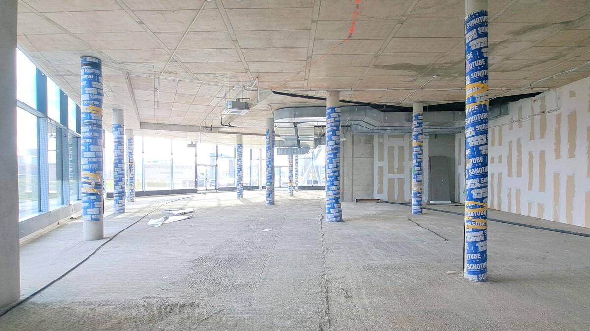Weiterer Blick in den Rohbau des Geschäftsraums mit zahlreichen Säulen und großen Fensterfronten.