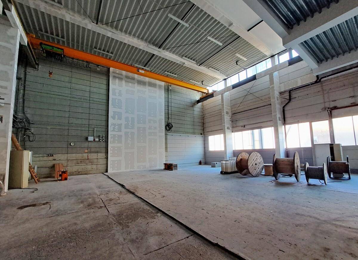 Geräumige Industriehalle mit hoher Decke, Kranbahn und großen Fenstern für natürliches Licht.