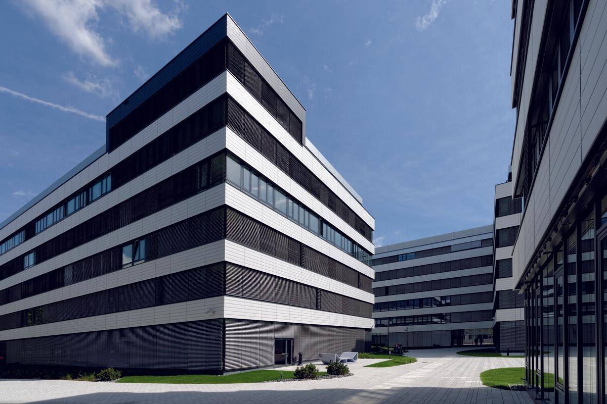 Ansicht eines modernen Bürokomplexes mit markanter Fassade und klarem Himmel.