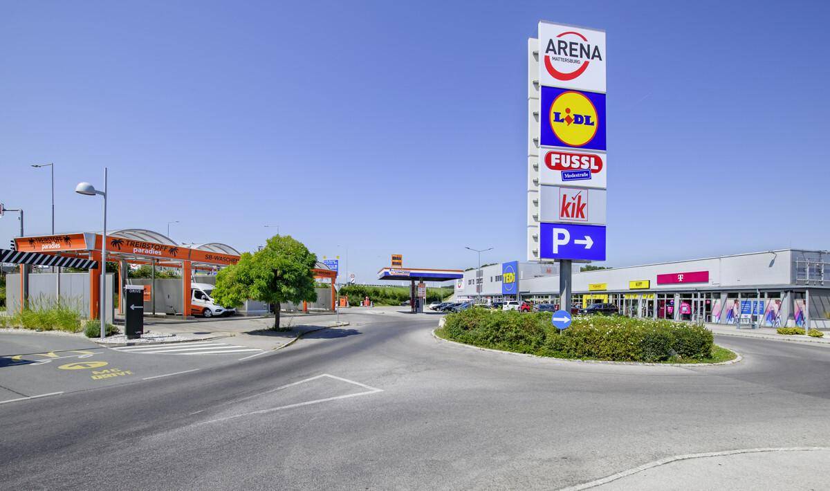 Gewerbegebiet mit einem großen Werbeschild, einer Tankstelle und einer Autowaschanlage.