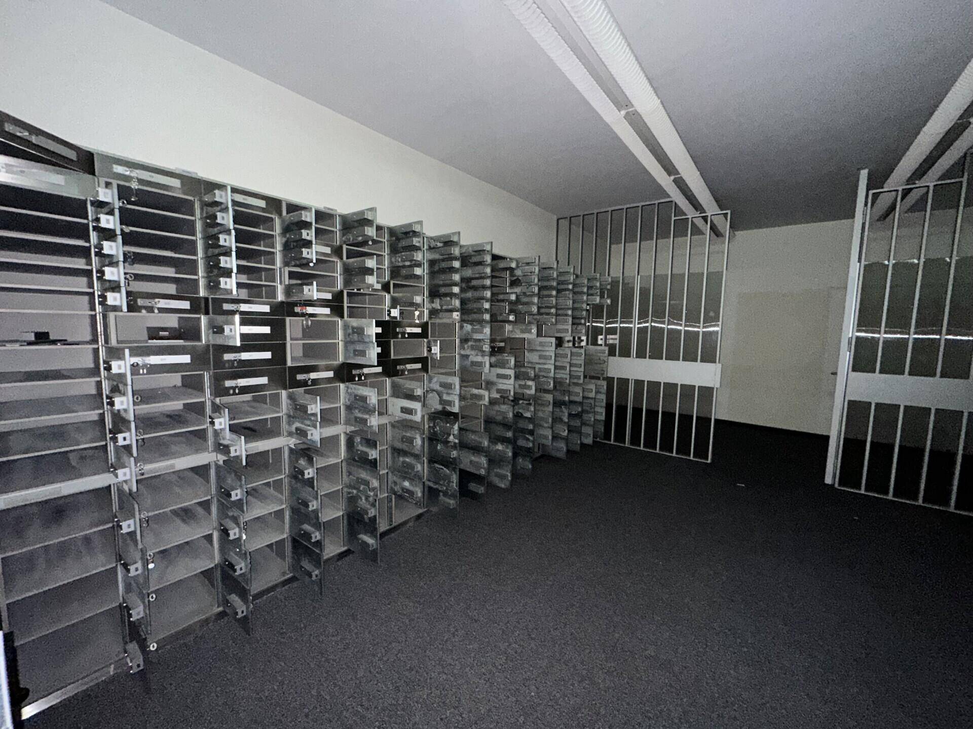Raum mit zahlreichen Schließfächern und Gittertüren, möglicherweise ein Tresorraum oder Archiv.