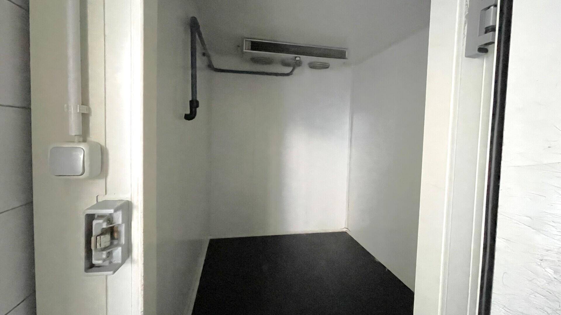 Kleiner Abstellraum oder Technikraum mit dunklem Boden und sichtbaren Installationen an der Decke.