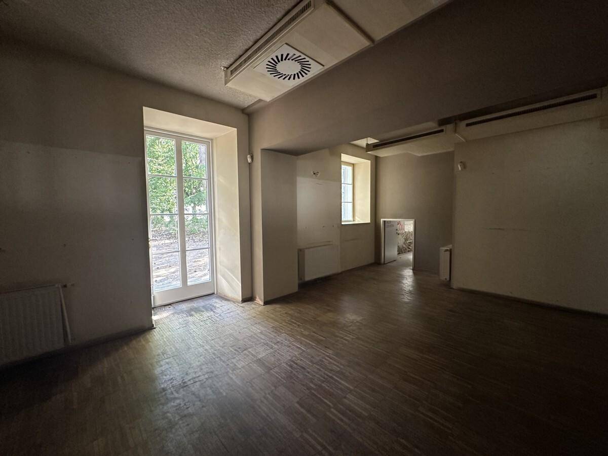Geräumiger Gewerberaum mit Holzboden, hohen Fenstern und einem Ausgang zum Außenbereich.