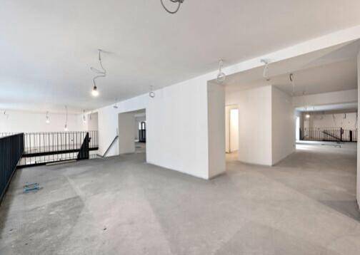 Großzügiger, offener Gewerberaum mit Betonboden und Blick auf die Galerieebene.